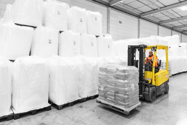 Un homme qui soulève une palette dans un chariot élévateur dans un entrepôt de logistique